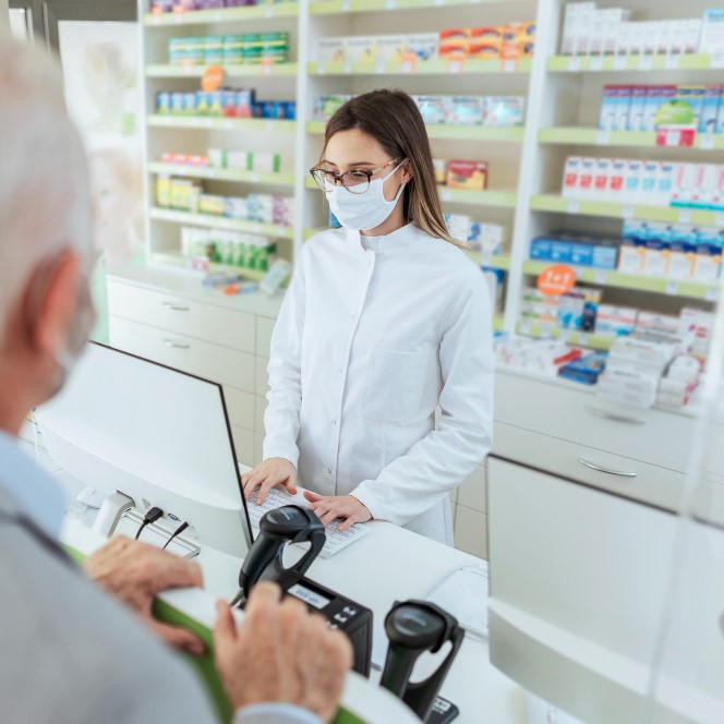 buying-and-selling-prescription-drugs-and-pharmacist-advice-an-adult-female-pharmacist-standing-behind-the-counter-and-selling-drugs-to-a-mature-man-she-is-wearing-a-protective-mask.jpg